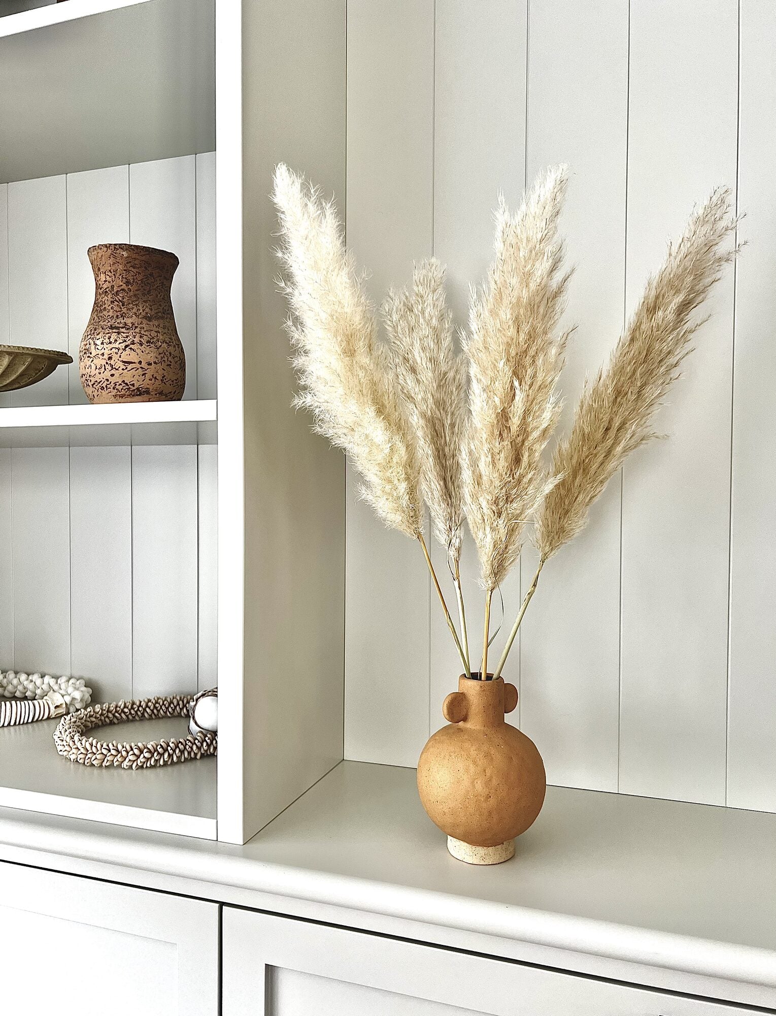Kleine natuurlijke pampas pluimen in een beige vaas als sfeervolle woondecoratie.
